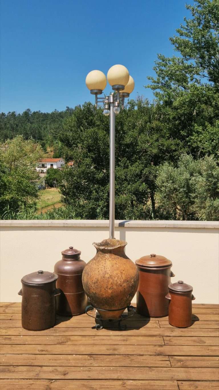 Peças de barro tradicionais no terraço, com a paisagem verde ao fundo