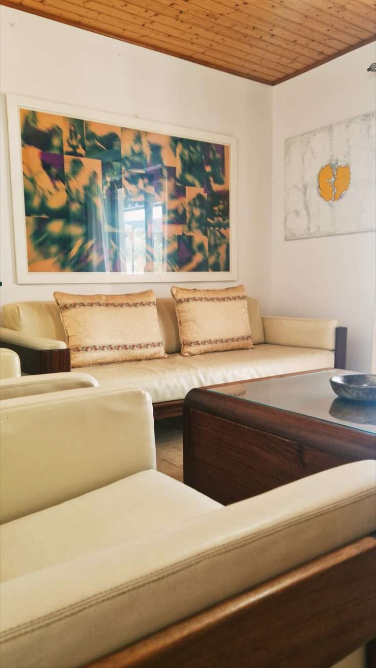 Sala com sofás claros, mesa de centro e teto de madeira