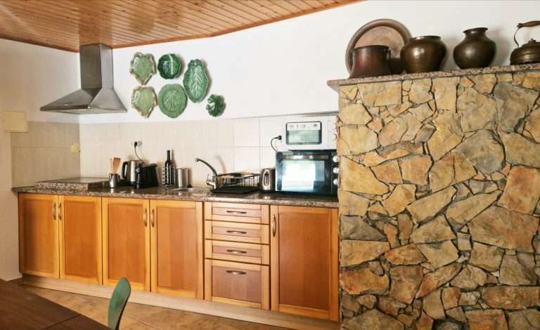 Kitchenette com móveis de madeira, fogão e bancada em pedra