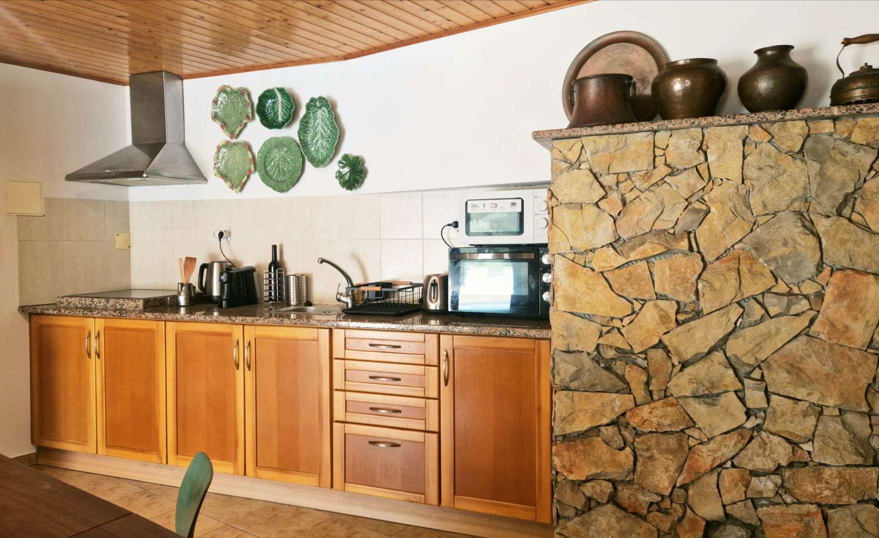 Kitchenette com móveis de madeira, fogão e bancada em pedra