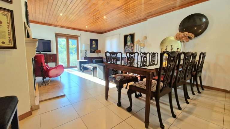 Sala de jantar com mesa de madeira, cadeiras e teto de madeira