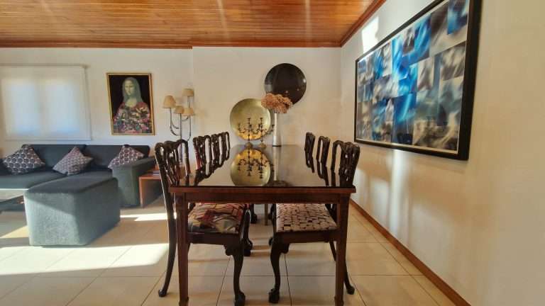 Sala de estar e jantar com sofá cinzento e mesa de madeira