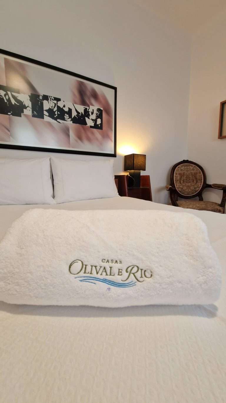 Toalhas bordadas com a marca Casas Olival e Rio sobre a cama