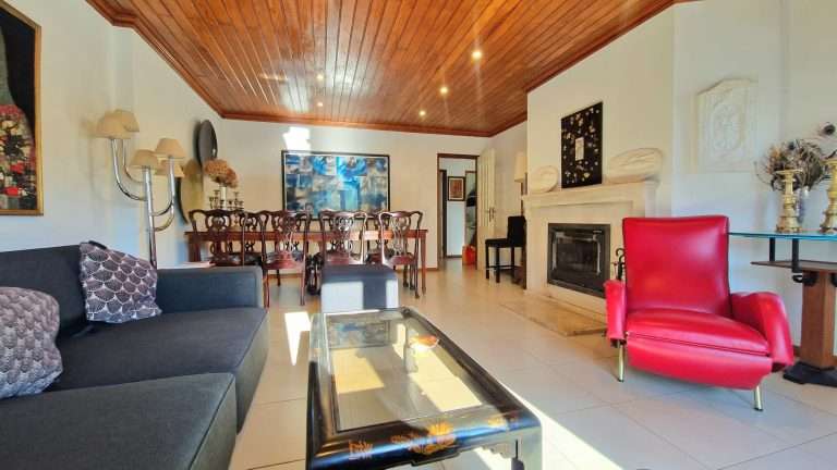 Sala de estar com sofá cinzento, poltrona vermelha e lareira