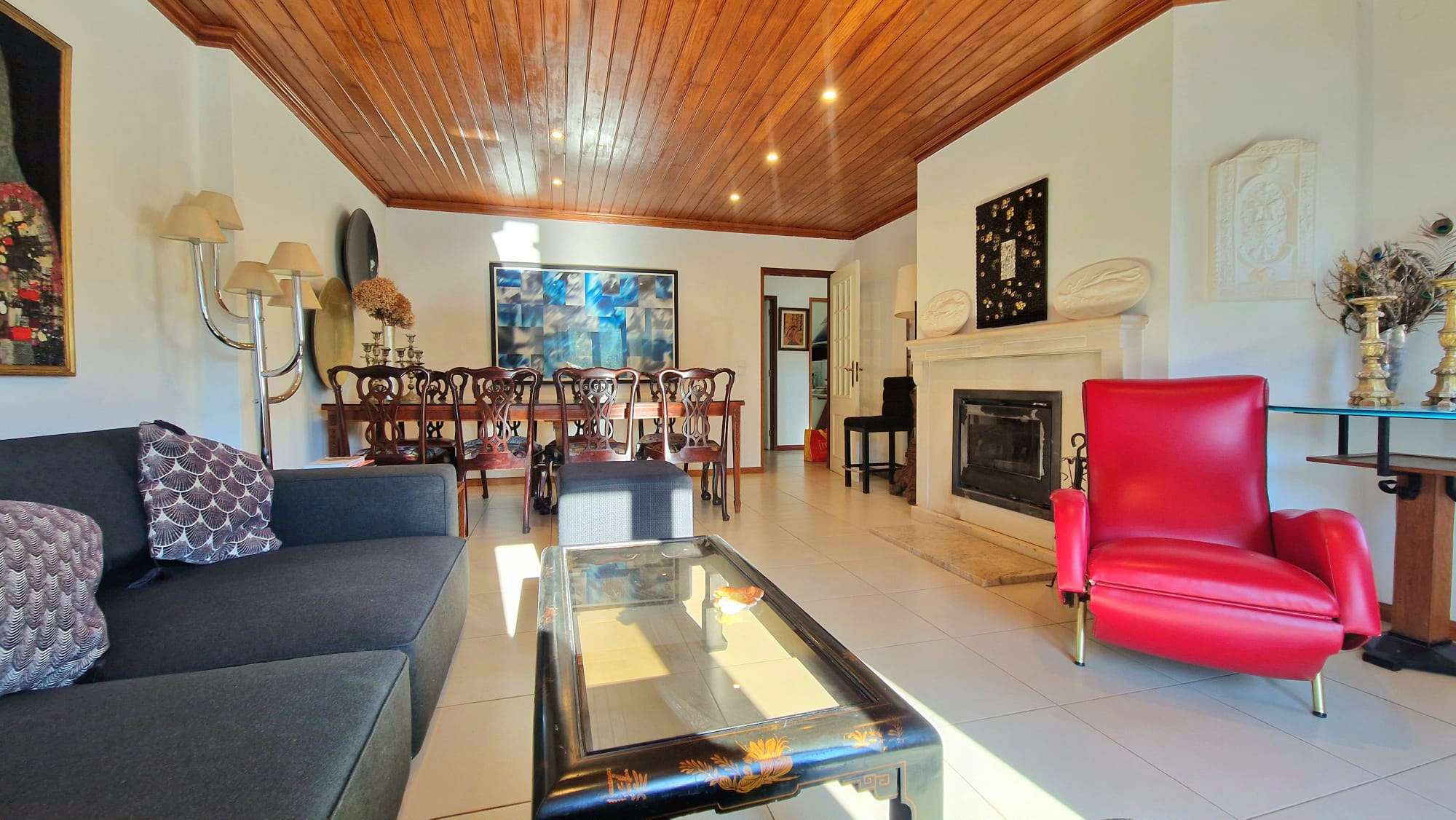 Sala de estar com sofá cinzento, poltrona vermelha e lareira