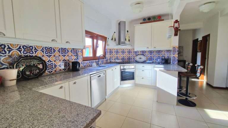 Cozinha equipada com móveis brancos e azulejos decorativos