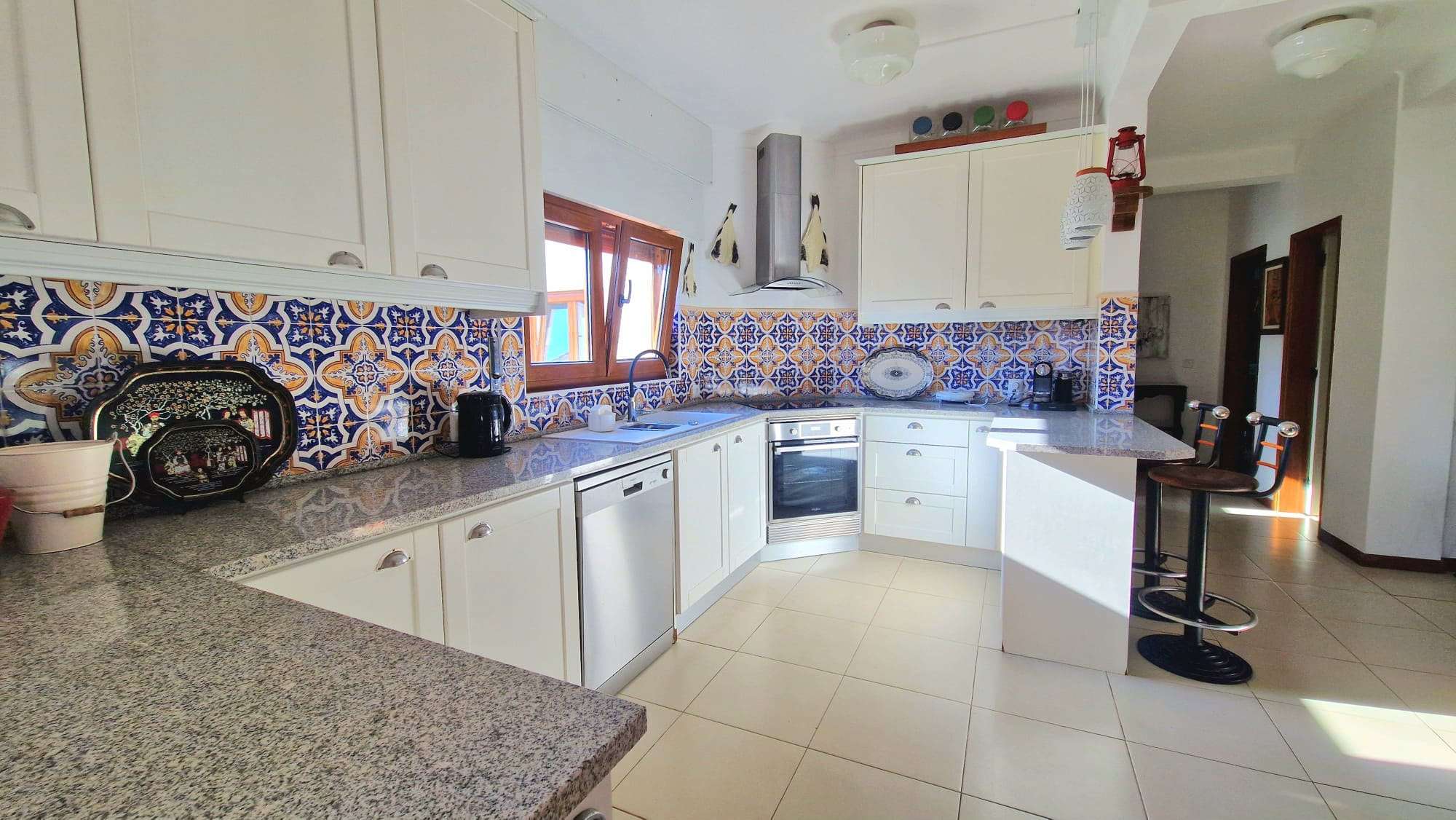 Cozinha equipada com móveis brancos e azulejos decorativos