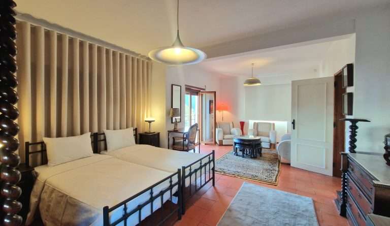 Quarto com camas individuais e zona de estar ao fundo