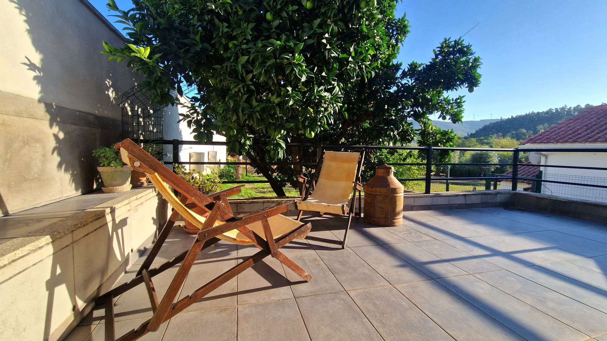 Terraço com cadeiras de madeira e vista para a paisagem verde
